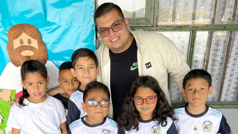 David, a ChildHope teacher, standing with 6 of his students